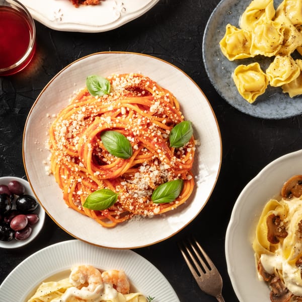 Overhead view of various Italian pasta dishes, including spaghetti, tortellini, and fettuccine with shrimp.